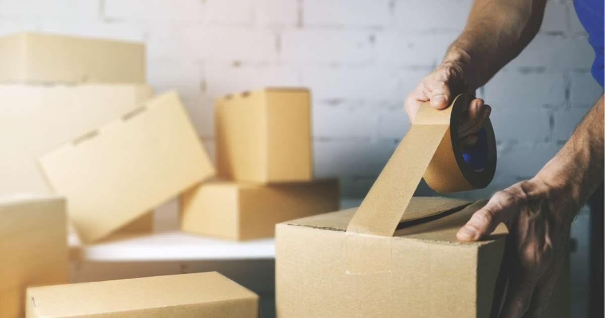 A Greenville packing professional taping a box with cardboard boxes in the background