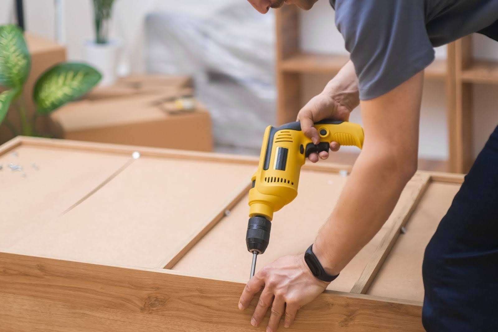 Custom white glove delivery professional fixing fasteners on wooden cabinet back side with professional screwdriver.