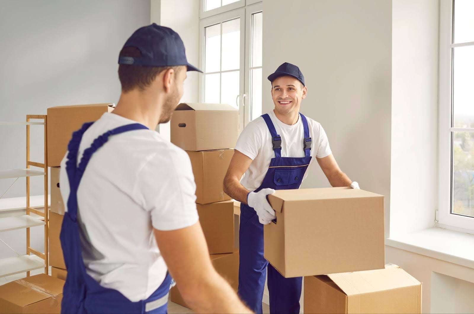 two movers smiling at each other while carrying boxes